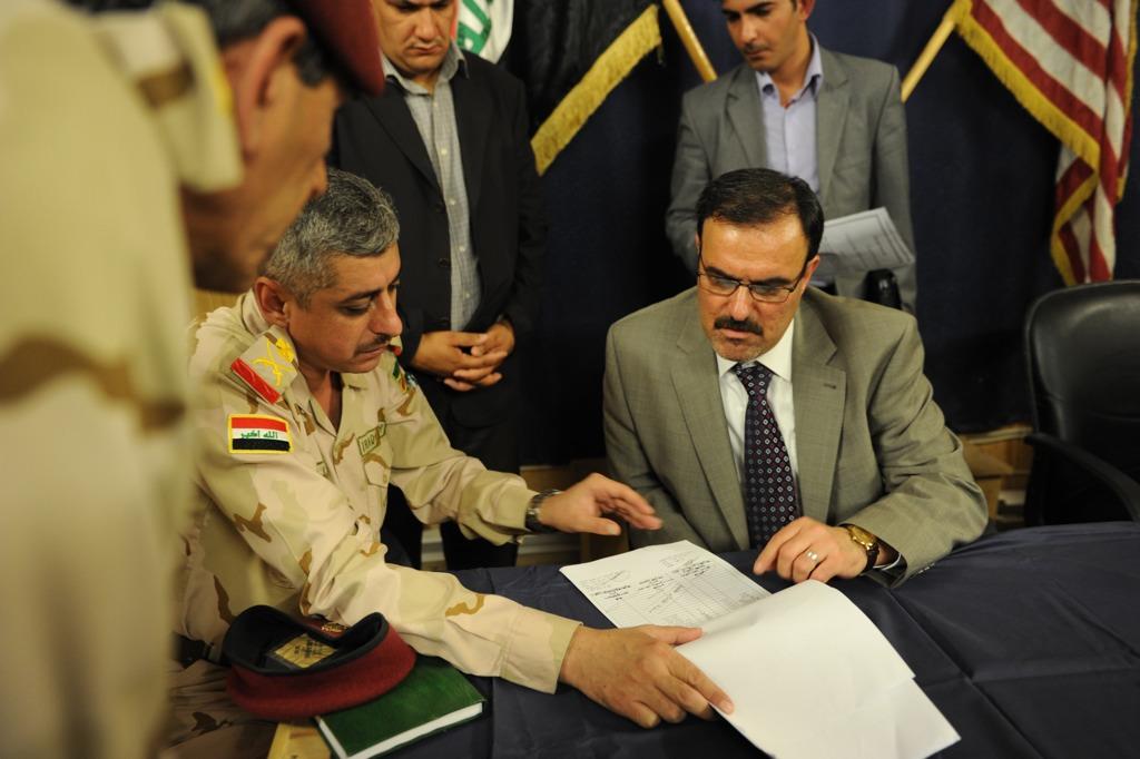 Sameer Alhaddad, receivership secretariat, signs documents returning the Forward Operating Base Mahmudiyah to Iraq