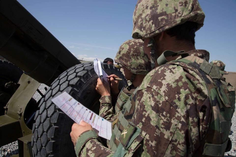 Afghan National Army (ANA) soldiers with the Kandak 201st corps write down coordinates, for a D30 howitzer target area, given from forward observers during a live fire field artillery exercise on