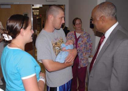 Mom Caylene Ackeret and dad, FC2(SW) Anthony James Ackeret show off their second child Micah Ezekiel to SEC Penn as he tours the renovated Maternal Infant Unit. Looking on is ENS Melissa Earhart, NC.