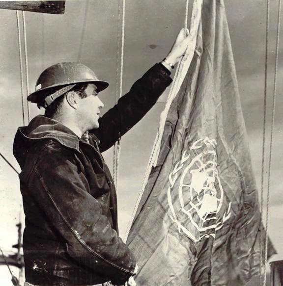 Page 4 of 10 Petty Officer Robert Stewart raises United Nations Ensign on HMCS Cayuga, flagship of Captain Brock, in 1950 photograph.