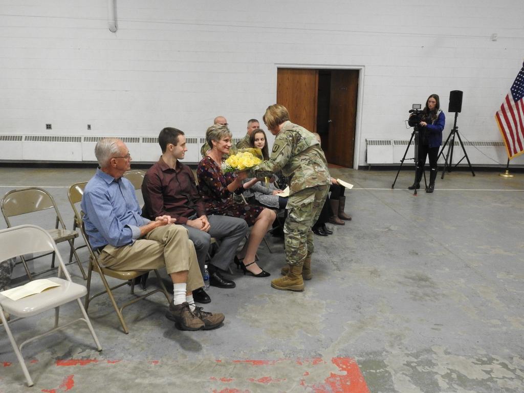 Photo #3 - CW3 McDuffie presents yellow flowers to COL Hallenbeck s spouse, Deb, on behalf of the soldiers, and families of the Camp Grayling Joint Maneuver Training Center.