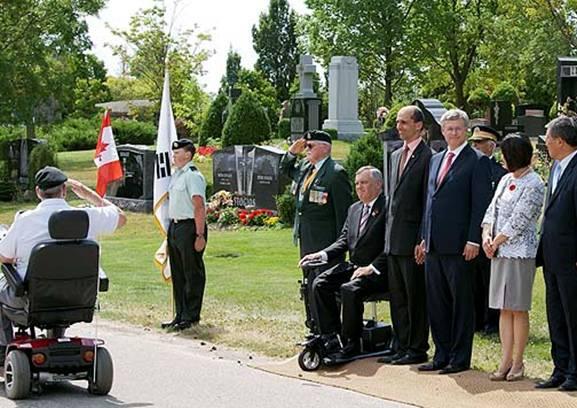 Senator Yonah Martin and Prime Minister Stephen Harper proudly acknowledge veterans marching past in review.