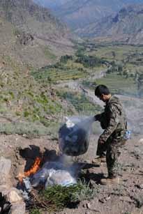 An Afghan National Army Soldier burns trash at a mountaintop observation post in eastern Afghanistan s Kunar Province Sept. 21.  U.S. Army Pfc. Duane A. Cheyne of Hopkins, Mich.