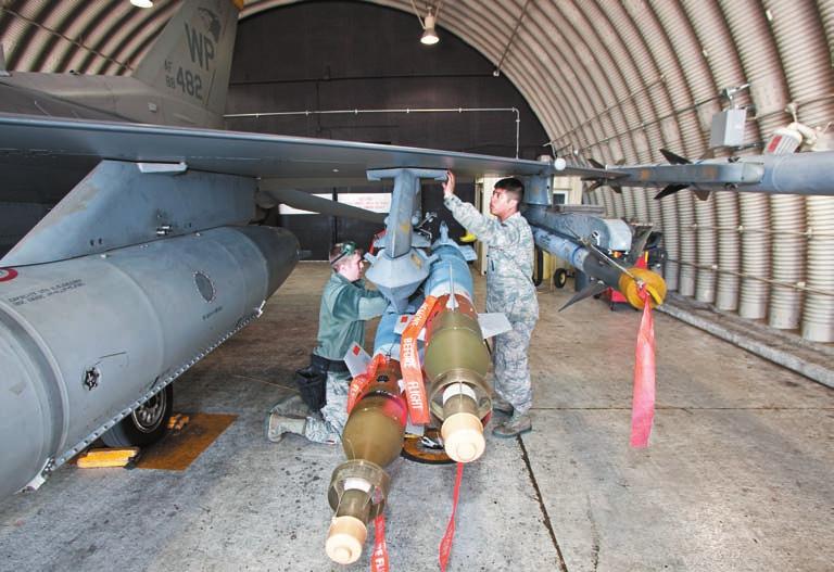 SrA. Bradley Denny (l) and SSgt. Jose Sanchez install practice GBU- 2 laser guided bombs on an F-6 s pylon.