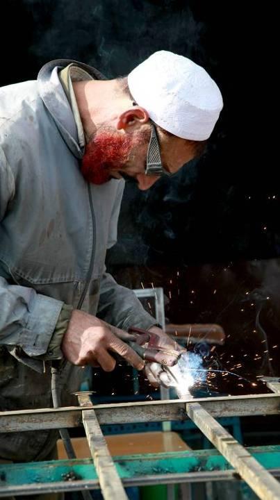 An Afghan local welds the end of a fence in Logar Province, Afghanistan, December