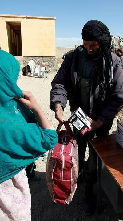 An Afghanistan National Policeman gives a radio and blankets to an Afghan woman in Logar Province, Afghanistan, October 22, 2009.