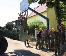 CEMENT BONDS Above: Croatian ingenuity comes into play: a Croatian engineer raises three of his soldier in a bucket loader while the soldiers and Airmen on the ground situate the basketball standard.