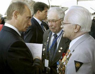 Russian President Vladimir Putin, left, speaks with his fellow countrymen, Oleg Ozerov, center, and Gleb Plaksin,