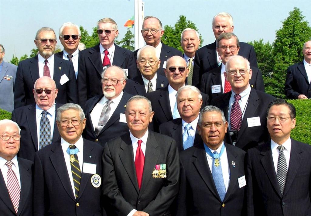 Lieutenant General Stephen Olmstead (USMC, Retired), is flanked by Korean War Medal of Honor recipients Hiroshi Hershey Miyamura and Joe Rodriguez, and surrounded by other Korean War veterans who