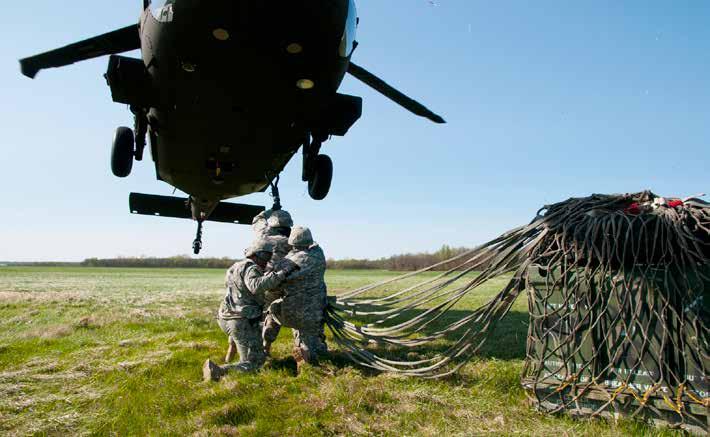 Soldiers from the 700th Brigade Support Battalion, Oklahoma Army National Guard, latch supplies onto a hovering UH- 60 Black Hawk helicopter during their annual training at the Sustainment Training