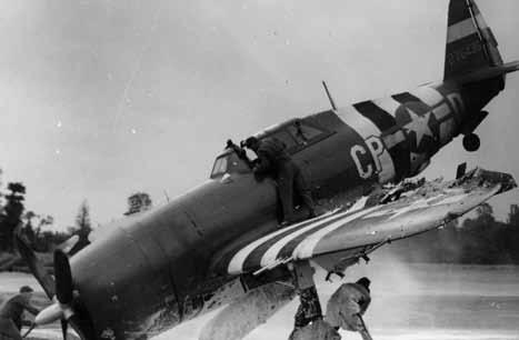 Battle scarred. Ground crew members rush to use foamite to extinguish a fire that started when the wounded pilot of this heavily damaged P-47 crash-landed at a newly created base in France.