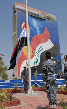 An Iraqi National Police honor guard salutes the raising of his national flag at a ground breaking ceremony signifying the Airport Road revitalization project July 5 in southern Baghdad.