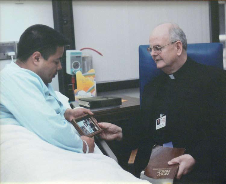 Father Patrick Kenny visits with an inpatient.