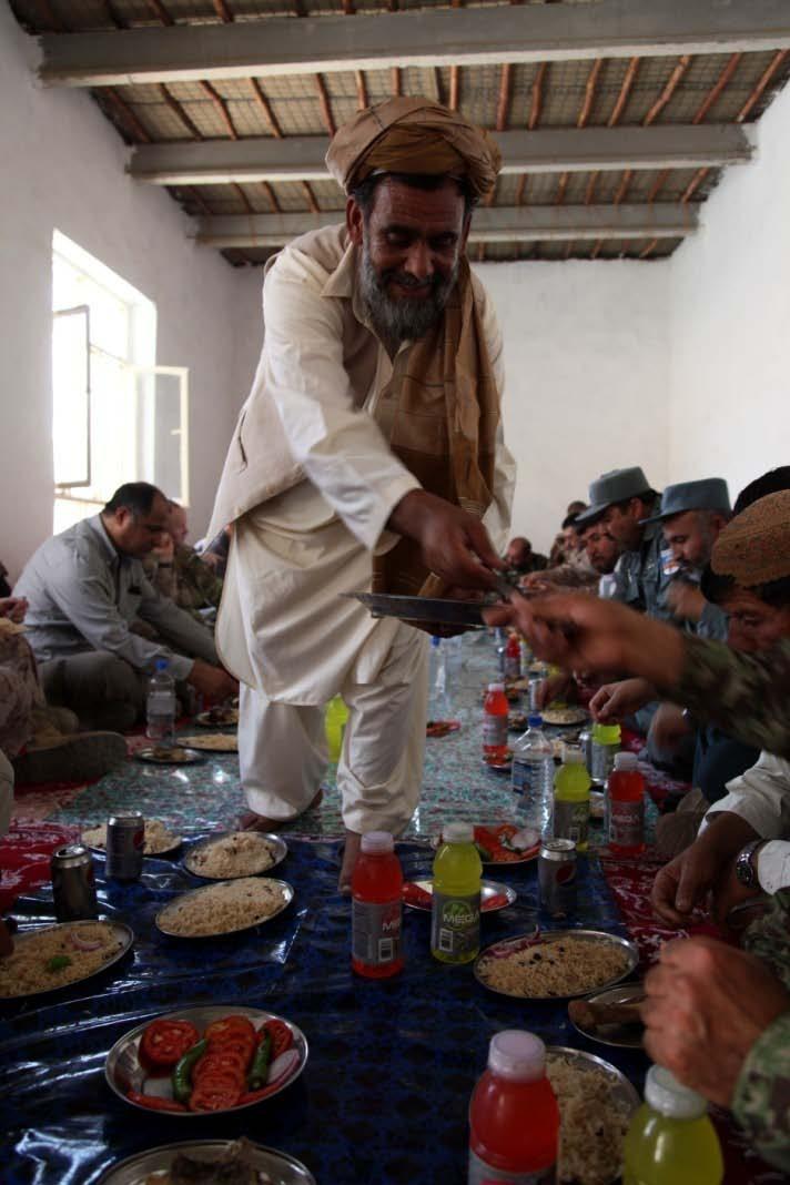 120627-M-KH643-099 An Afghan national hands out spoons during a traditional Afghan meal at the Delaram District Center, Nimroz province, Afghanistan June