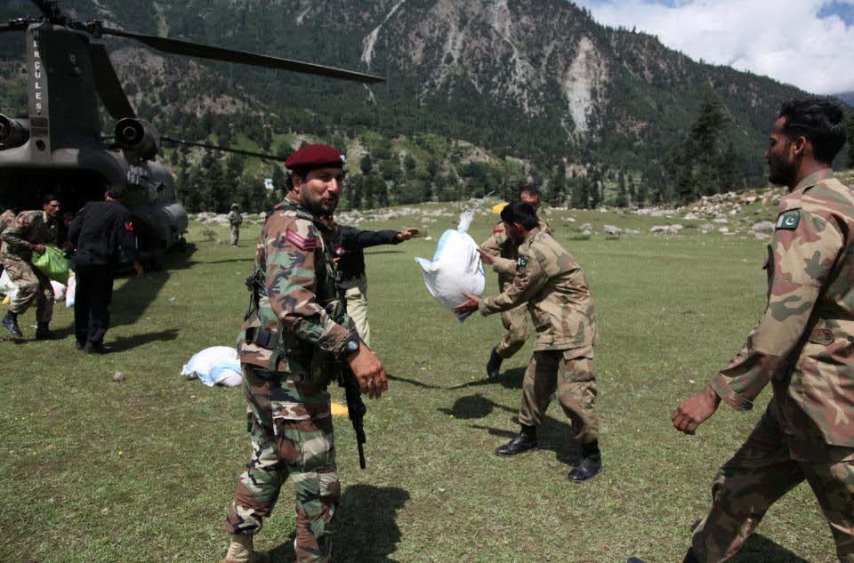 Pakistan military members pass along bags of grain as they unload the back of a U.S.