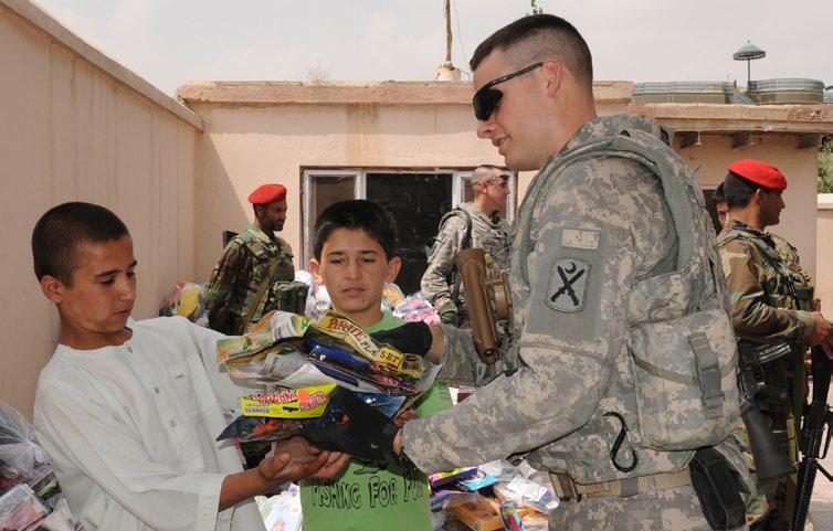 Maj. Edward Michels, 1st Battalion, 178th Field Artillery, South Carolina Army National Guard, gives two boys a handful of toys during a humanitarian aid drop Aug.