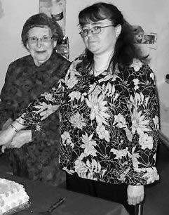 Forteau Local entertainer, Lisa Davis (left) cuts the cake with Herselia Flynn, President of the Labrador South Health Centre Auxiliary, at the volunteer dinner held on Friday, May 5, 2006, in