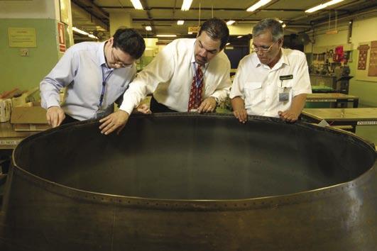 [ ] >> TOP, LEFT: Tony Hagen (center) of Commercial Airplanes Singapore office inspects an engine exhaust nozzle with Singapore