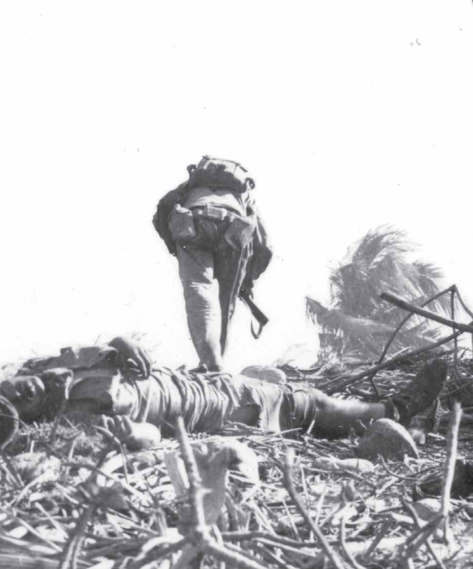 A Marines passes a dead Japanese soldier as he