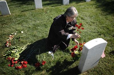 Deborah Peterson places flowers at the grave of her brother, Marine Cpl. James Chandonnet Knipple, at Arlington National Cemetery.