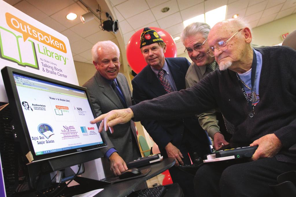 Vineland Veterans Memorial Home resident Norm Baker, right, indicates on the Outspoken Library Kiosk the service where he downloads books to, left right, Adam Szczepaniak, director of the New Jersey